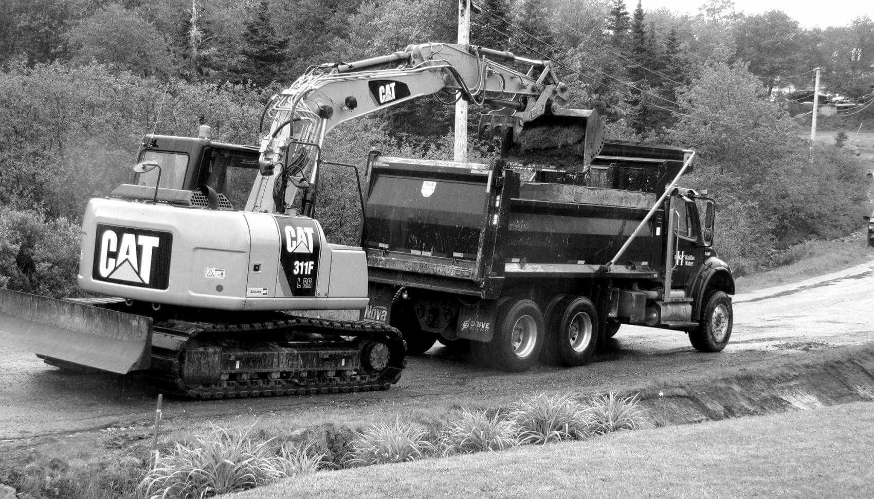 Cat backhoe digging a ditch and dumping the debris into a Halifax Water truck to be removed