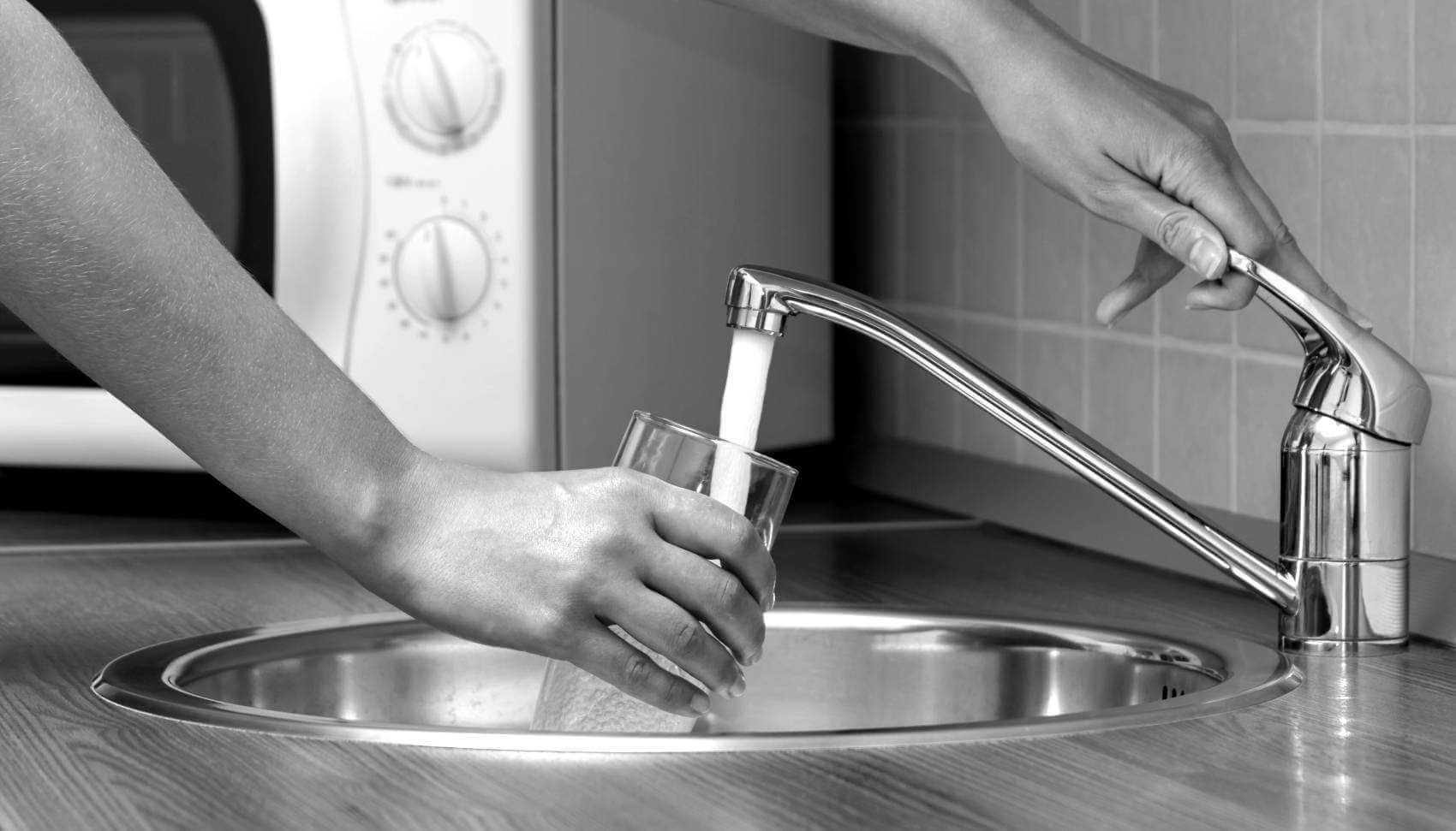 persons hands getting a glass of water from the tap