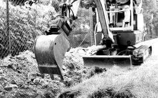 Small excavator digging in trench.